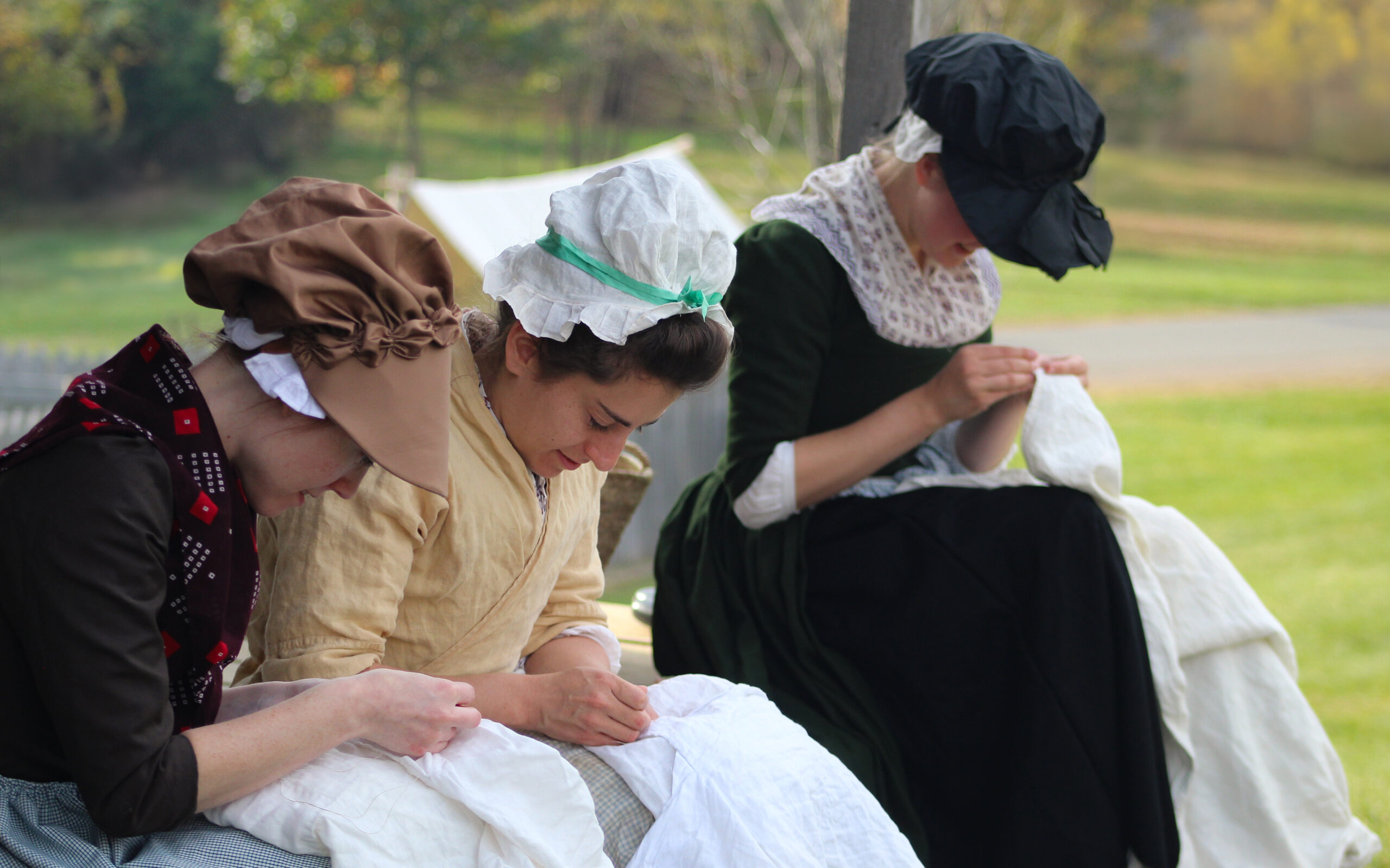 Historical reenactment of sewing and clothing repair in a military camp during the American Revolution