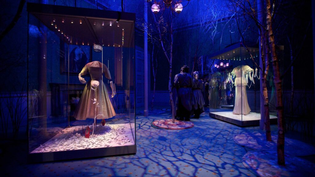 Extant gowns of late royals in an immersive history exhibition, blending theatre and fashion to reinterpret royal life in a historic palace setting. (Photo courtesy of Wildworks.)