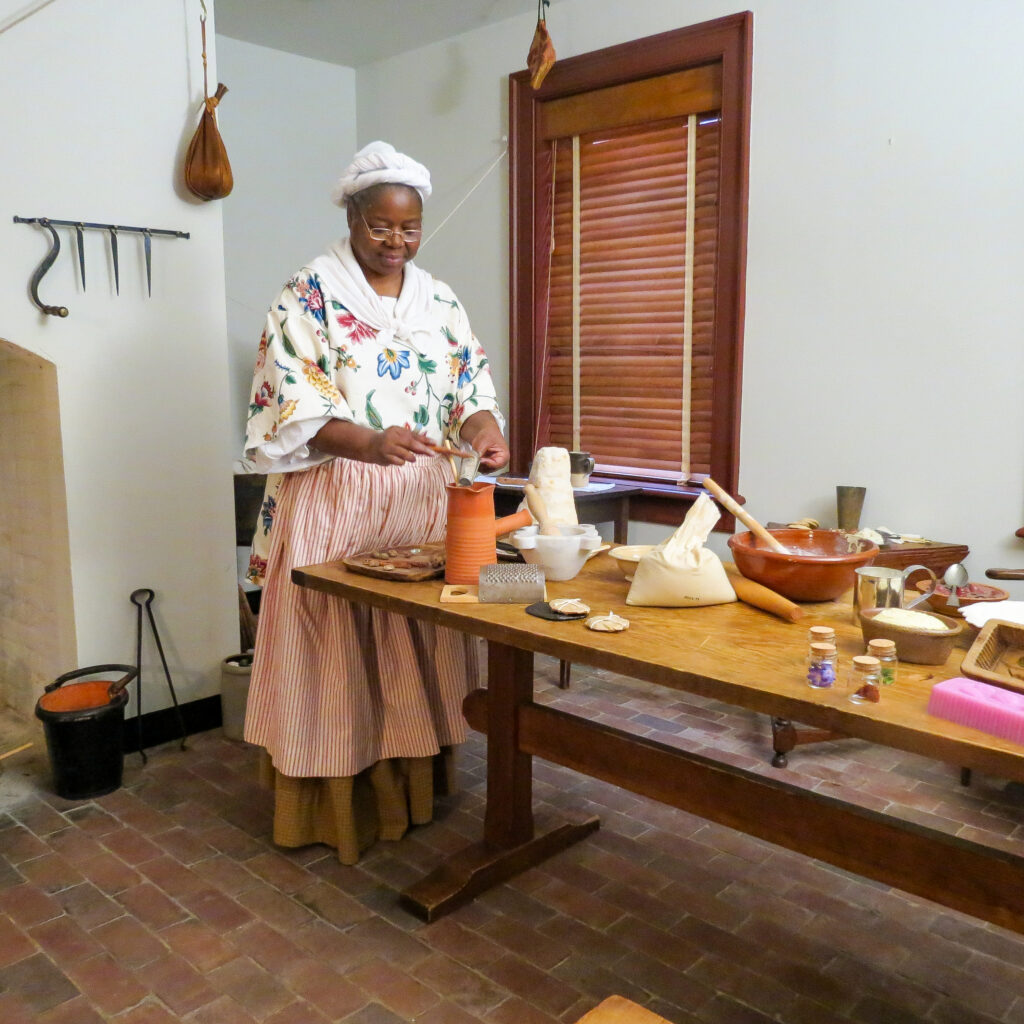 In the Kitchen. A reenactor portraying a cook enslaved by Paca prepares hot chocolate in the kitchen. 2025.