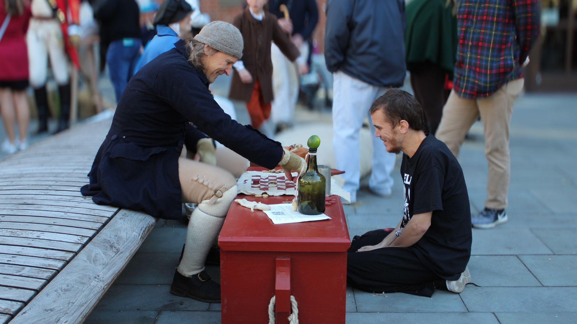 A sailor reenactor plays checkers with a visitor, captured through living history photography.