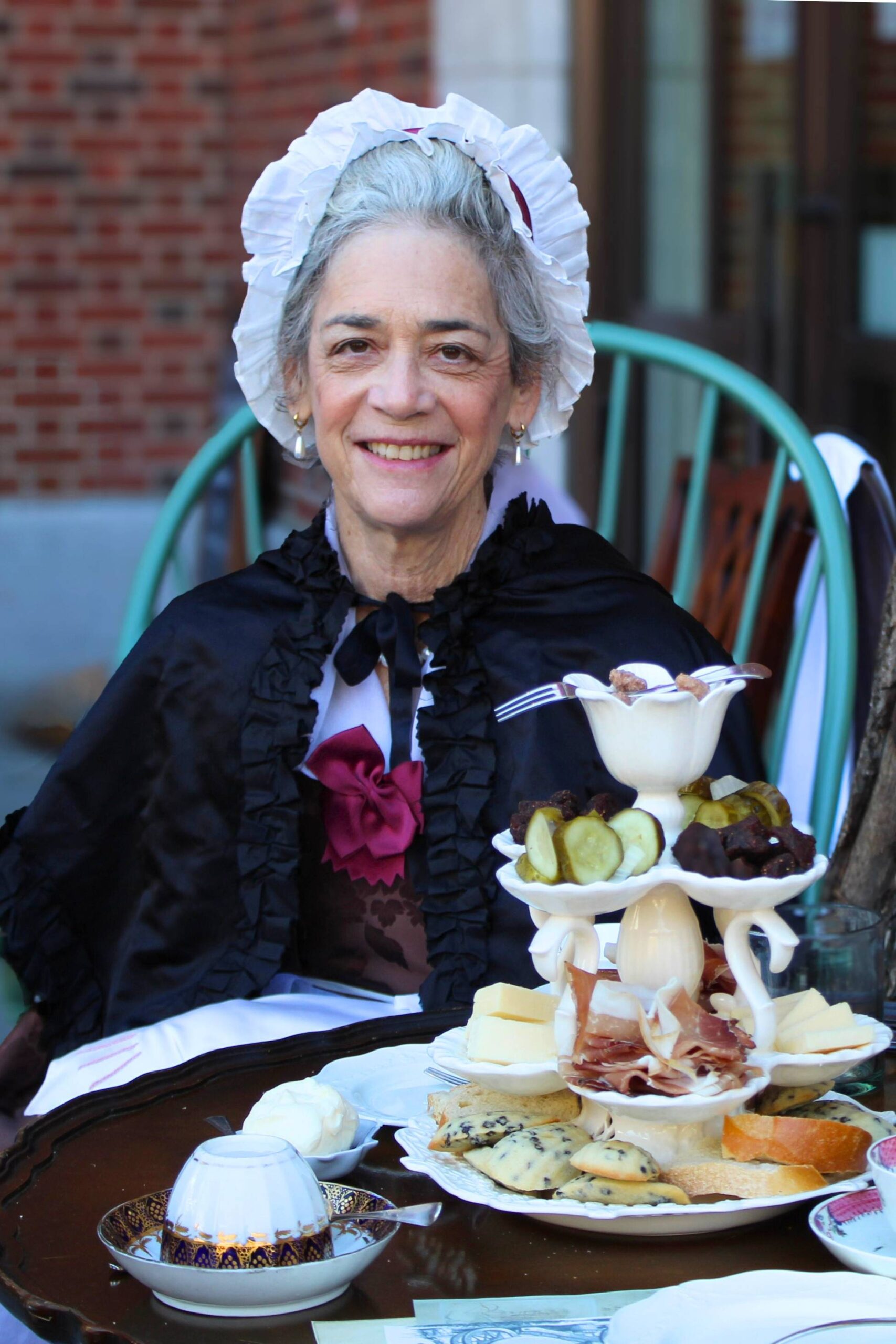 A reenactor portraying an elegant 18th-century woman with serving dish.