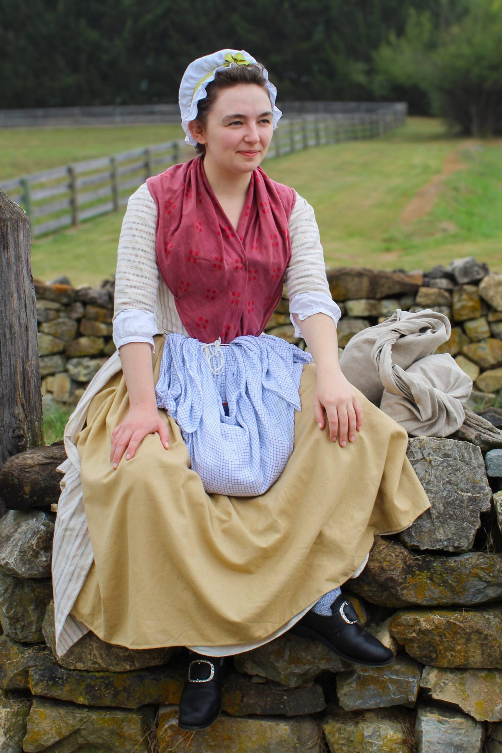 Reenactor, sitting on a stone fence in a living history photography style.