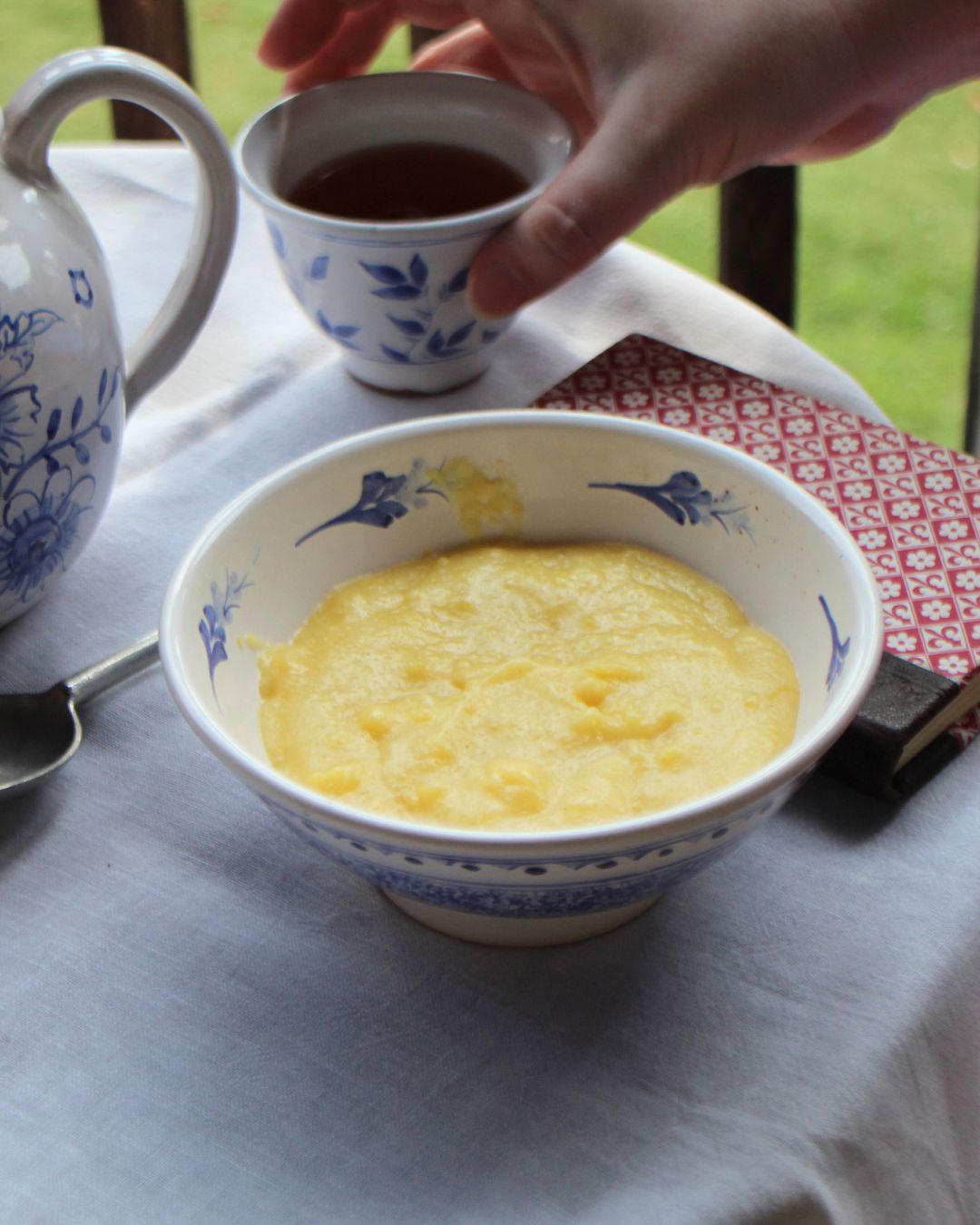 Grits and tea served in blue and white pottery, captured as an 18th-century dining scene through living history photography.